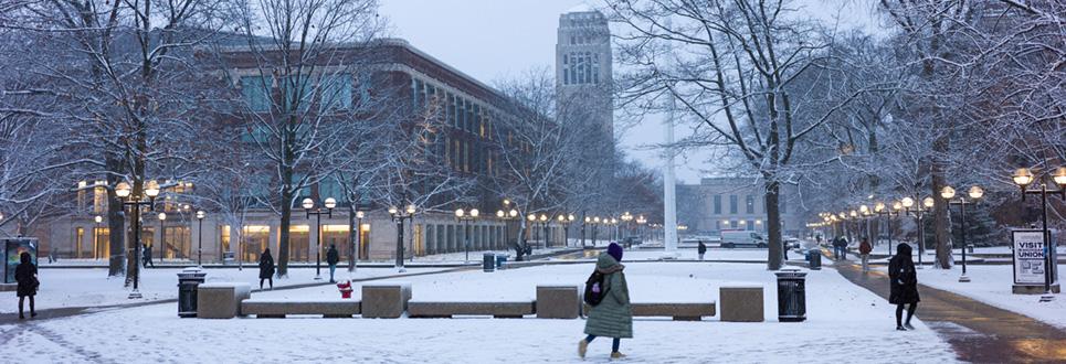 Student walking across campus in winter with snow on ground